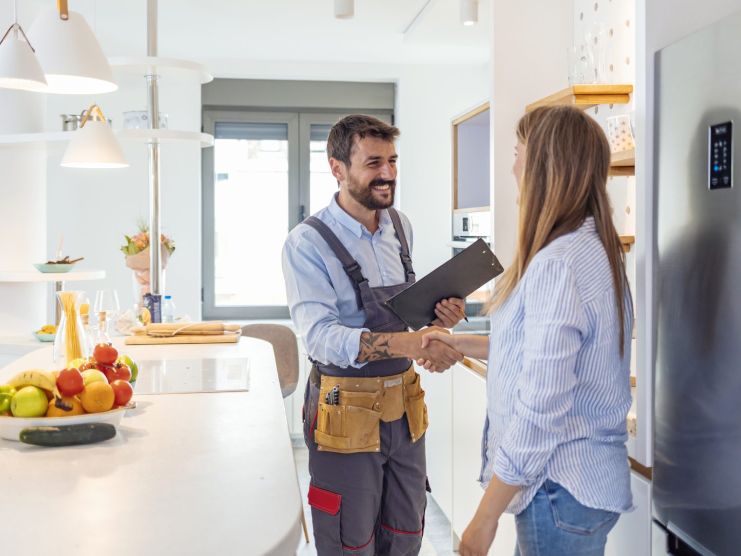 Young woman shaking hands to male inspector with clipboard in the kitchen.